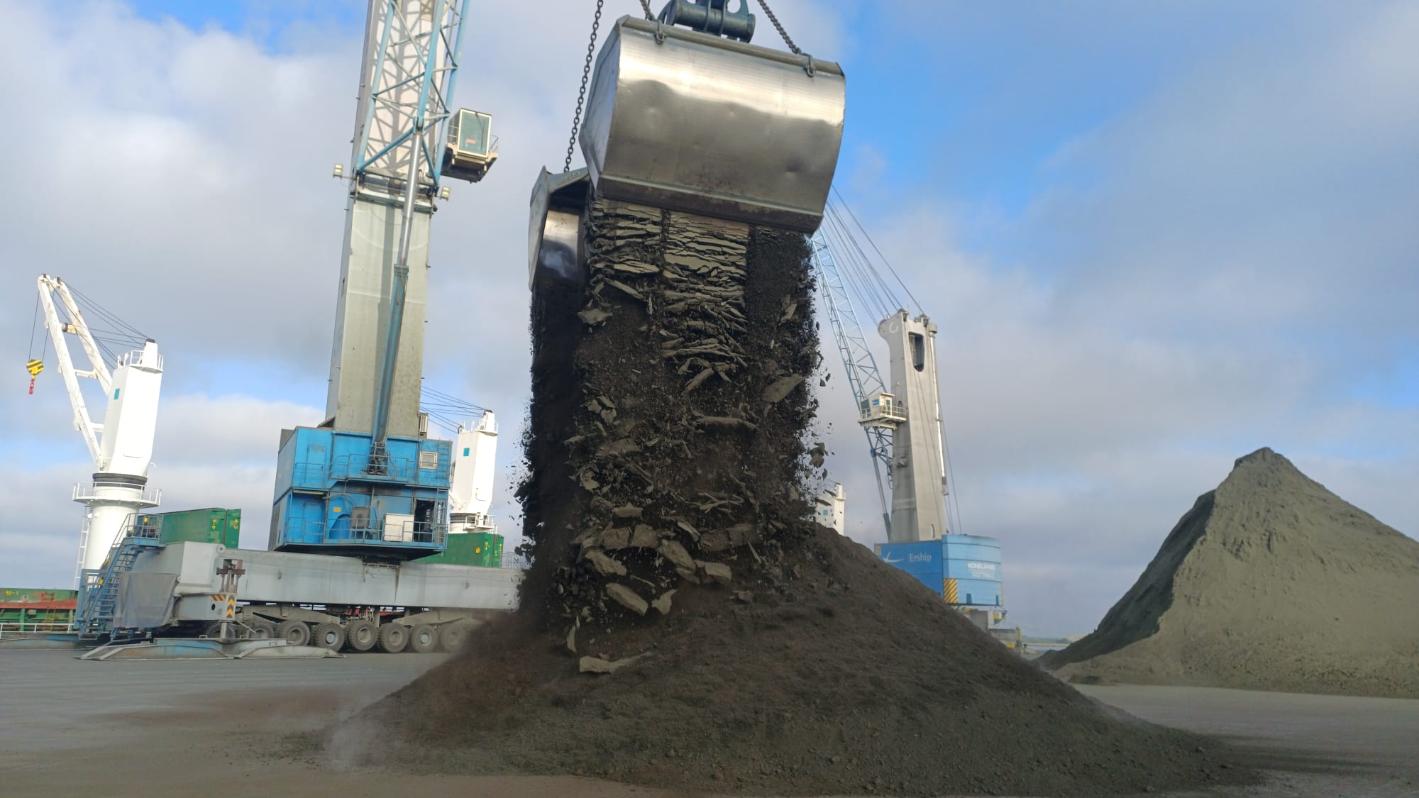 Crane grab discharging metal concentrate from a vessel under Bachelet supervision, Huelva