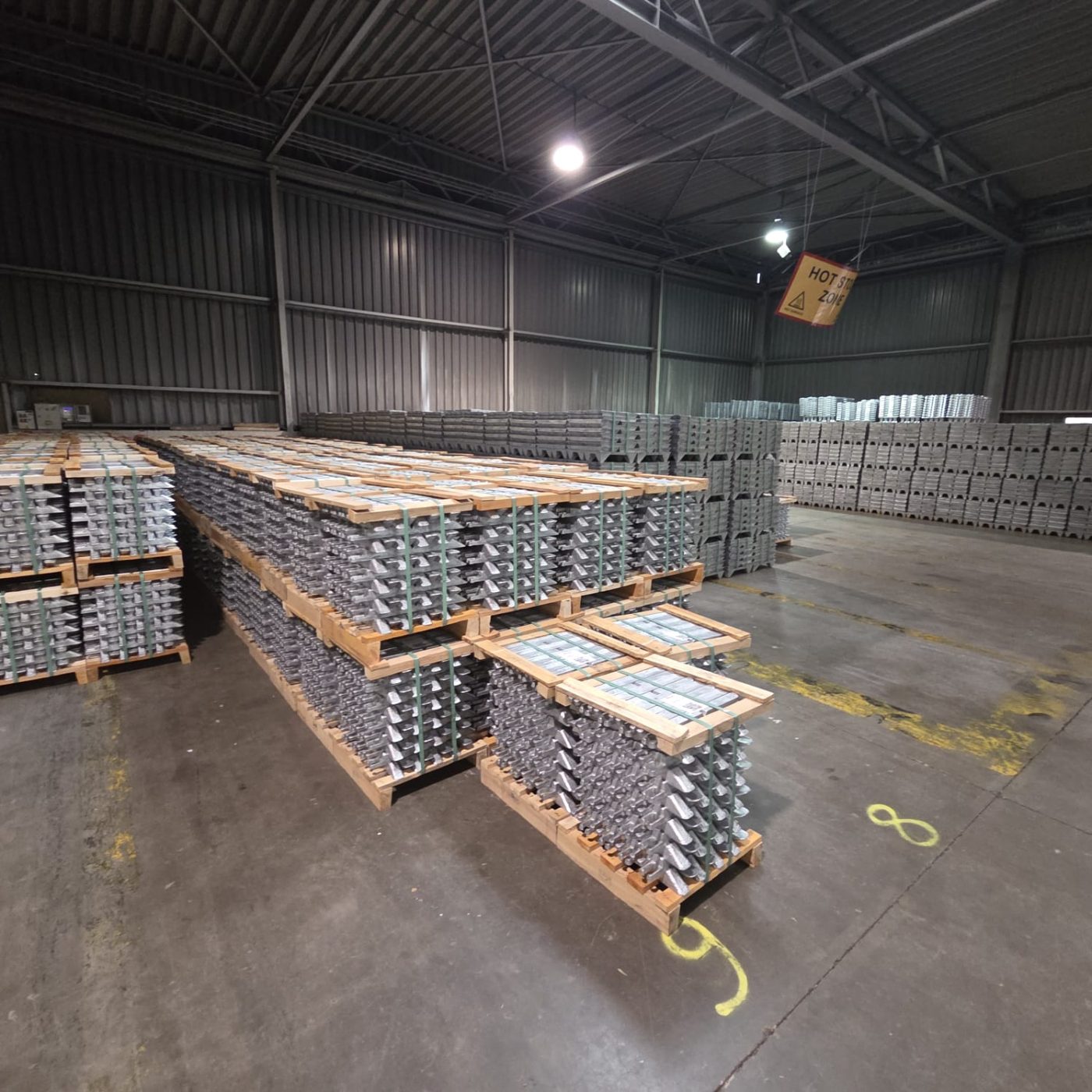 Palletised zinc ingot bundles in a warehouse stockyard under Bachelet stock and warehouse inspection