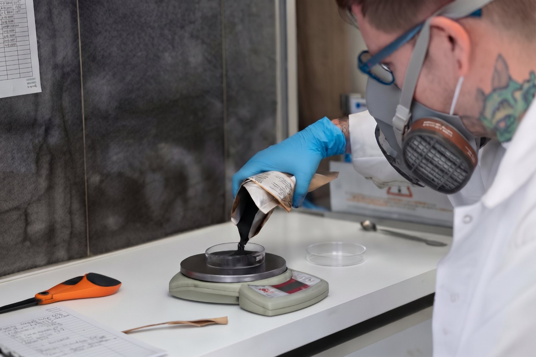 Analyst wearing a half-mask respirator while weighing ore concentrate at Bachelet